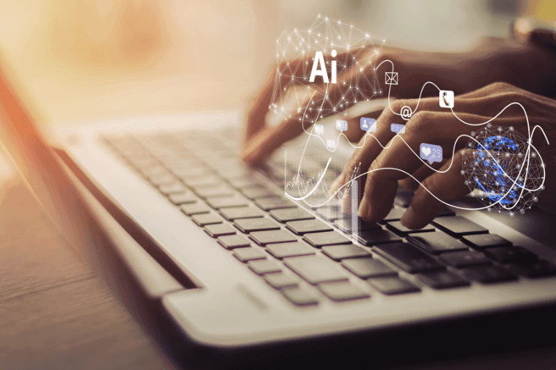 Hands typing on a laptop keyboard under a digital network of icons labelled “AI”